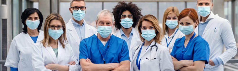 A group of doctors with face masks looking at camera, corona virus concept.